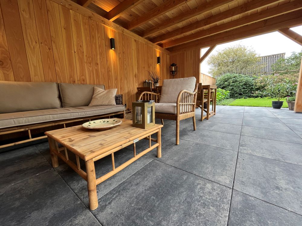 Het hout van de overkapping in combinatie met de meubels zorgt voor een sfeervolle omgeving